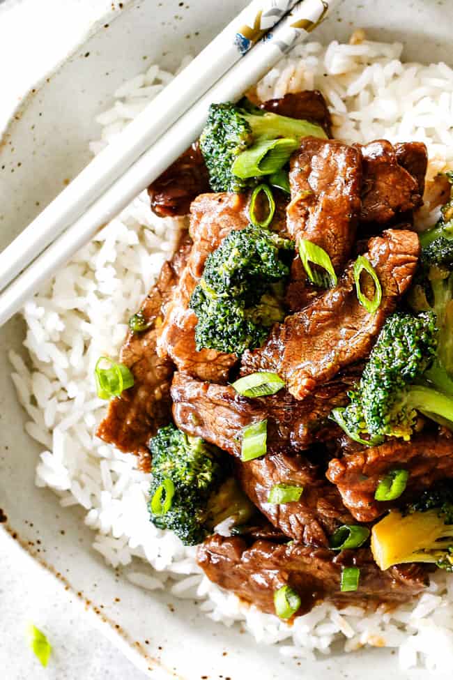 top view of best beef and broccoli recipe on white rice with green onions with chopsticks