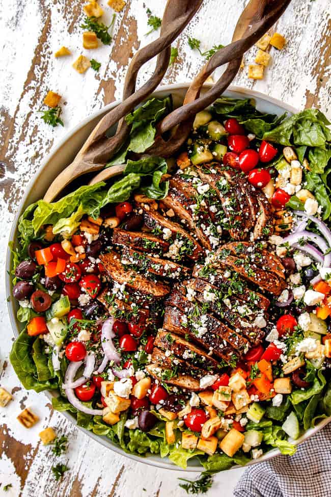 top view of Greek Chicken Salad with yogurt dressing in a white bowl with tomatoes, olives, cucumber, red onions and Greek Chicken