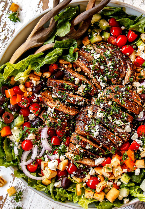 top view of Greek Chicken Salad with yogurt dressing in a white bowl with tomatoes, olives, cucumber, red onions and Greek Chicken