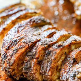 showing how to make Greek Chicken Salad by slicing chicken on a cutting board