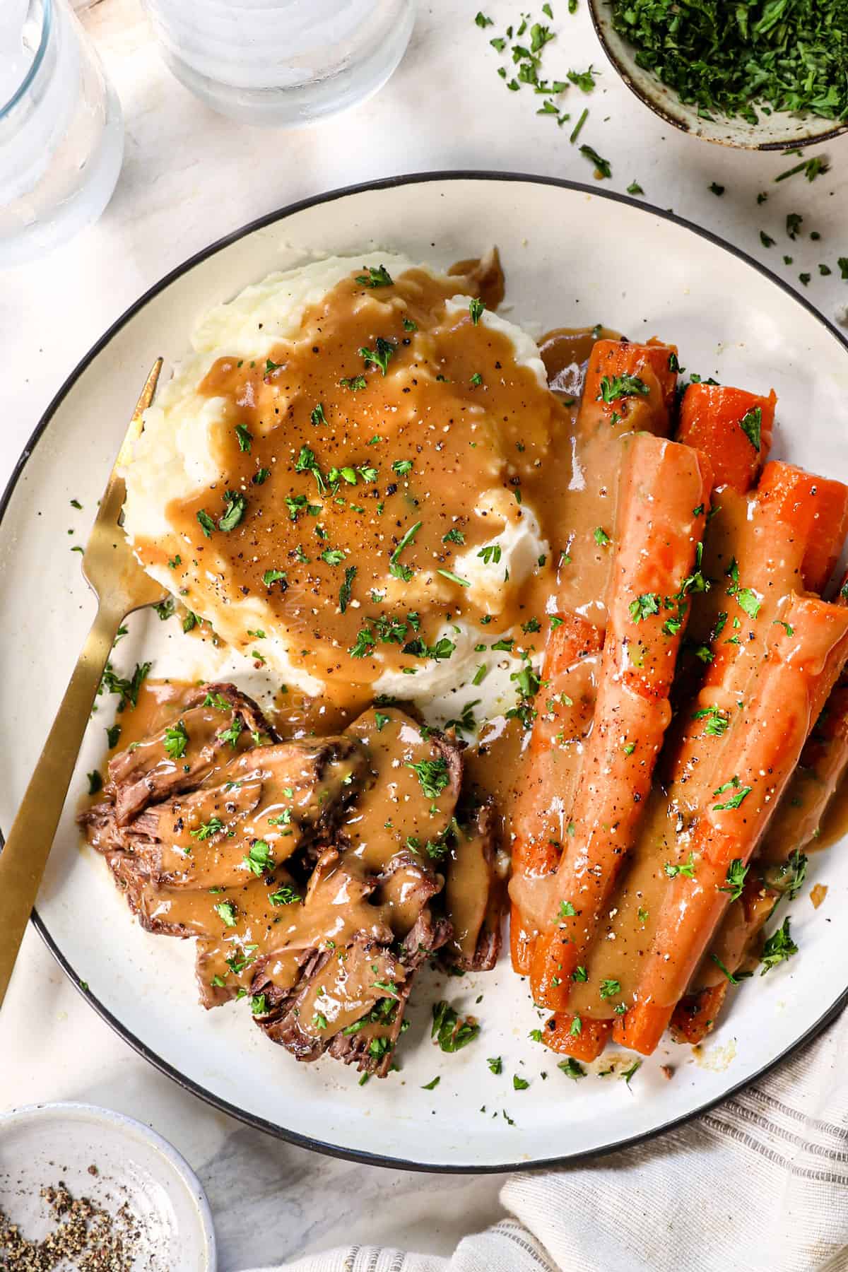 serving best pot roast recipe on a plate with potatoes and carrots and gravy