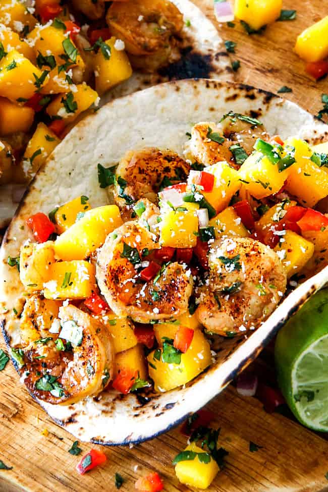 healthy Shrimp Tacos with Mango Salsa and Avocado on a wood cutting board 