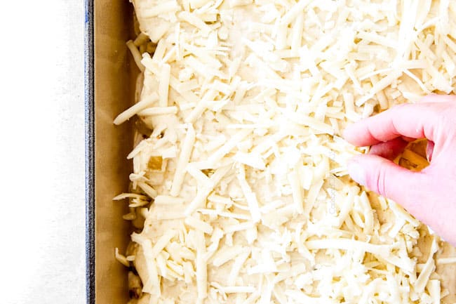 adding cheese to green chili chicken enchiladas in blue pan