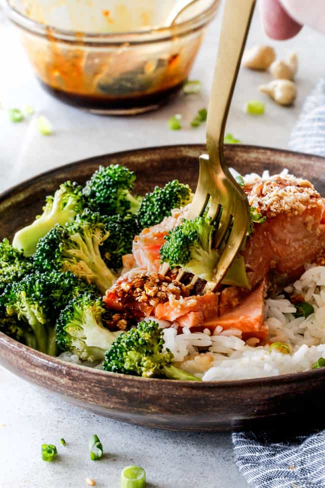 Fork in honey soy salmon with broccoli and rice in a brown bowl
