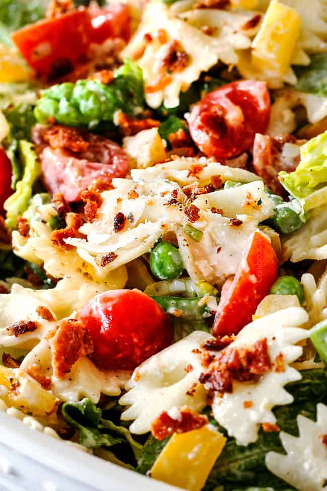 Up close side shot of easy BLT Pasta Salad recipe in a white bowl with one fork spearing pasta