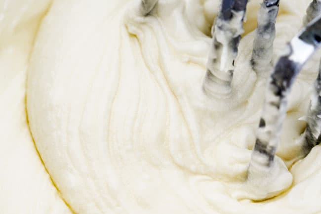 How to make easy Coconut Cake by making coconut frosting in the mixer with cream cheese, butter, cream of coconut and powdered sugar