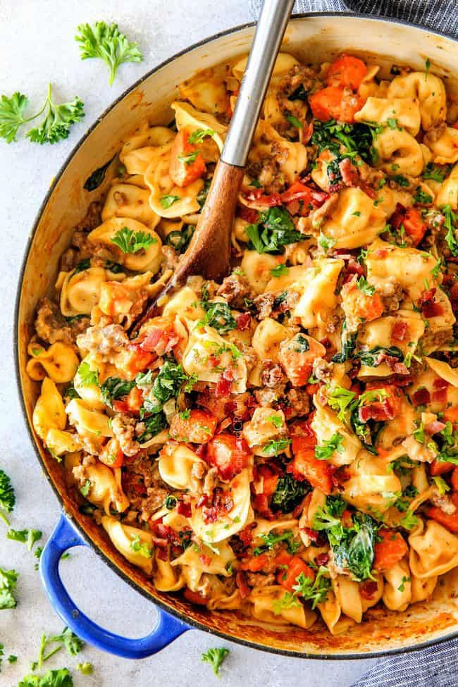 Top view of Creamy Tortellini recipe in a large skillet garnished with fresh Parmesan and bacon