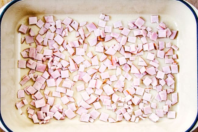 Showing how to make Eggs Benedict Casserole by layering Canadian Bacon in the bottom of a blue casserole dish