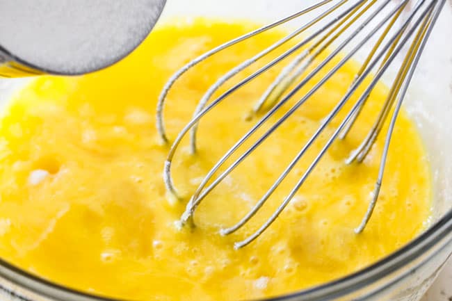 Showing how to make Lemon Curd for Lemon Blueberry Cake by whisking sugar into eggs in a glass bowl