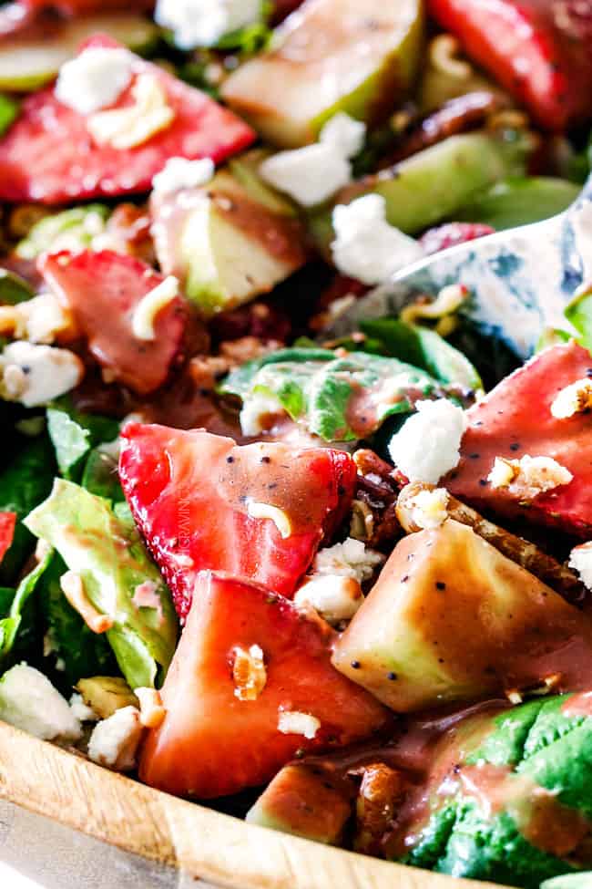 up close of strawberry salad with balsamic vinaigrette with strawberries and goat cheese in a wood bowl