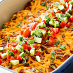 up close of cheesy Beef Enchiladas in a white baking dish