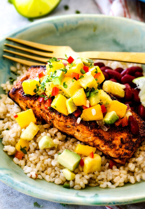 far away side view of cajun salmon in a green bowl with Pineapple, mango avocado salsa