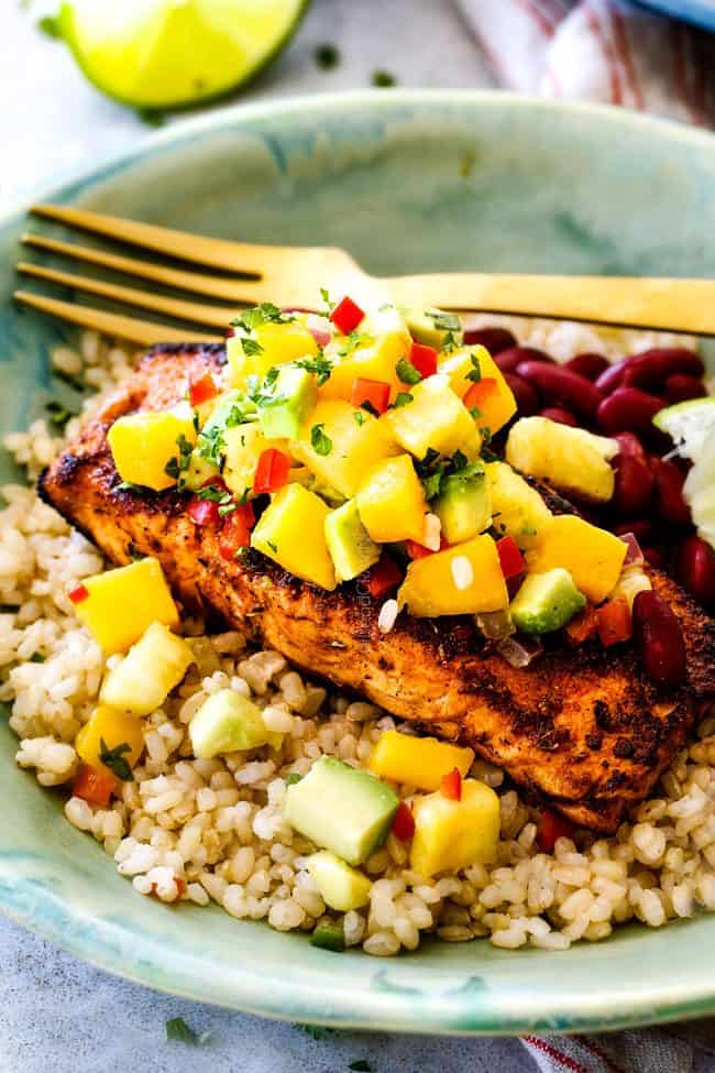 far away side view of cajun salmon in a green bowl with Pineapple, mango avocado salsa