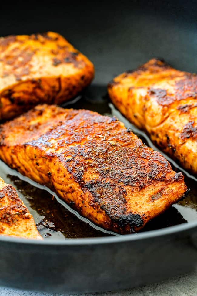 side view of cajun salmon in a black skillet being seared