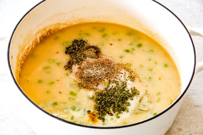 Showing how to make easy Chicken Gnocchi Soup by adding chicken and seasonings to soup in a white dutch oven