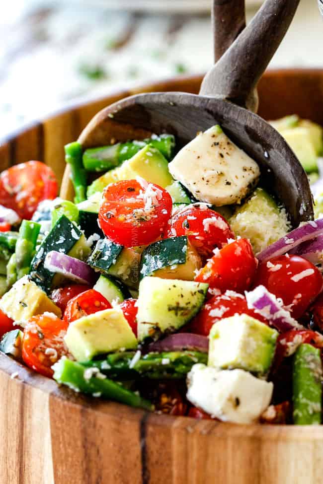 up close of Tomato Cucumber Salad recipe with cherry tomatoes, cucumbers, red onion, asparagus, mozzarella and avocado