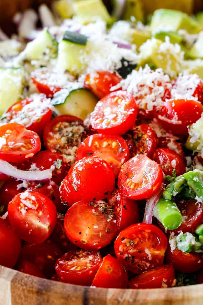 up close of Cucumber and Tomato Salad in a wood bowl with cherry tomatoes, cucumbers, onion, asparagus and avocado