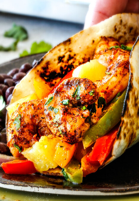 up close of oven roasted shrimp fajitas on a metal plate with bell peppers, onions and pineapple