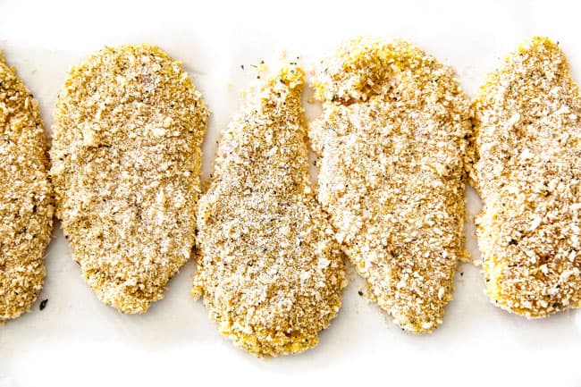 panko breaded chicken parmesan on a piece of white parchment paper resting before frying