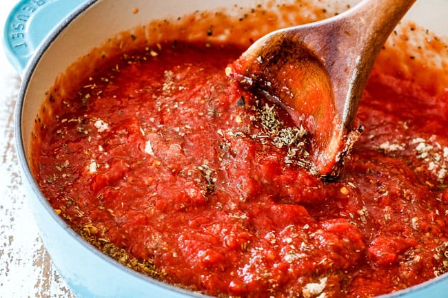 making homemade marinara for easy Chicken Parmesan with crushed tomatoes, basil, parsley, onion, garlic, thyme, oregano