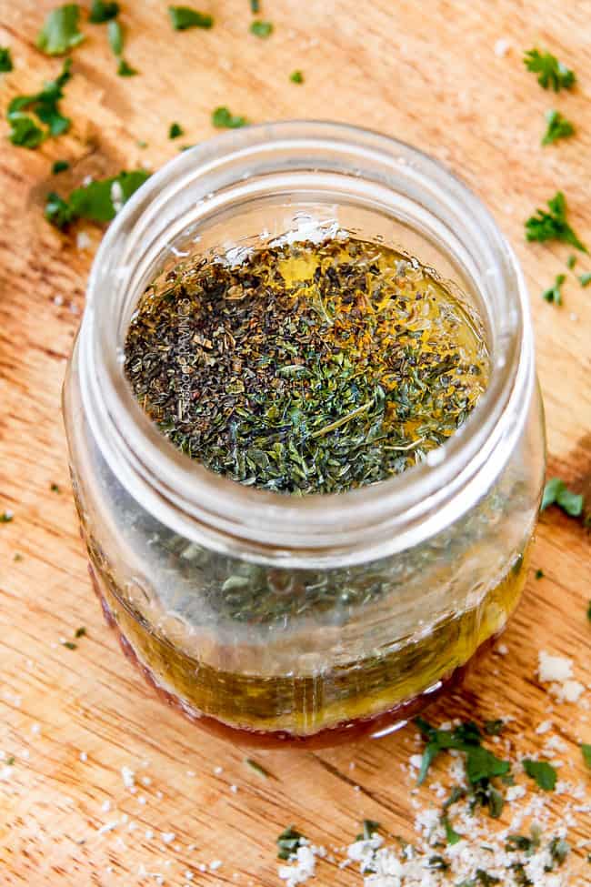 Showing how to make Homemade Italian Dressing by adding vinegar, oil, garlic, lemon juice, basil, parsley, oregano, salt and pepper to a mason jar