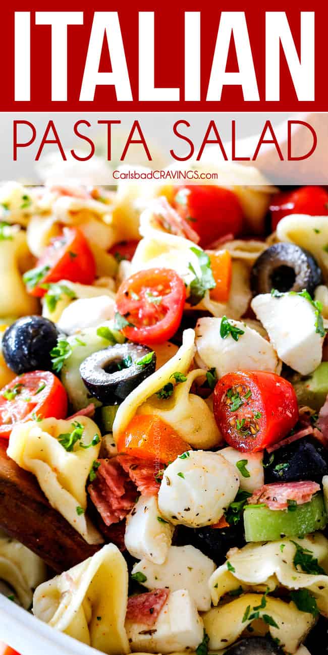 Cold Pasta Salad with Italian Dressing in a white bowl being tossed with wooden spoons