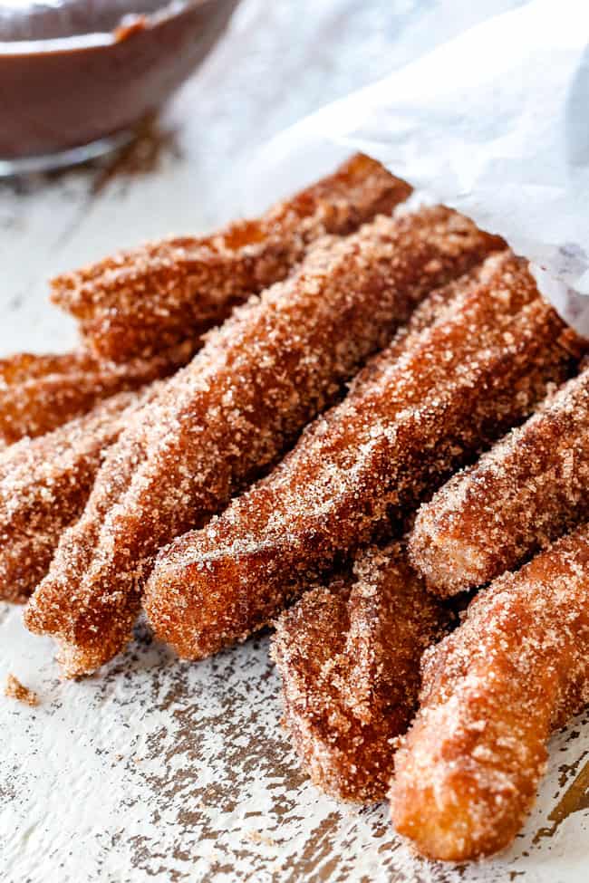 up close of homemade churros in a white bag laying on their side