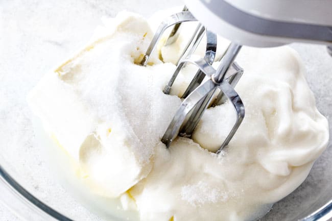 Showing how to make grape salad by adding cream cheese, yogurt and sugar to a glass bowl