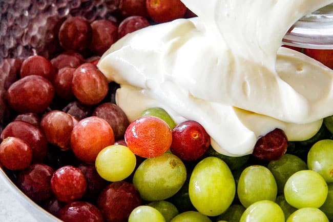 pouring cream cheese dressing over grapes showing how to make grape salad