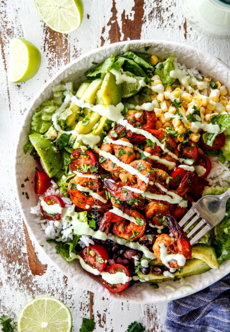 top view of shrimp Burrito Bowl with chipotle shrimp, tomatoes, avocados, corn, black beans and rice drizzled with cilantro lime dressing