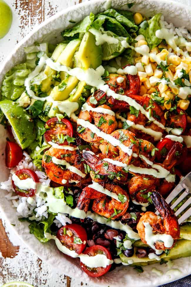 top view of Burrito Bowl with shrimp, tomatoes, avocados, corn, black beans and rice drizzled with cilantro lime dressing