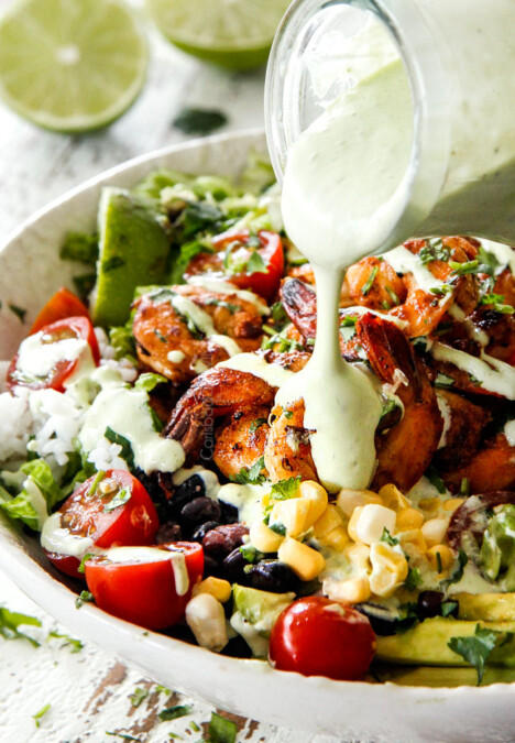 pouring Cilantro Lime dressing over shrimp in burrito bowl