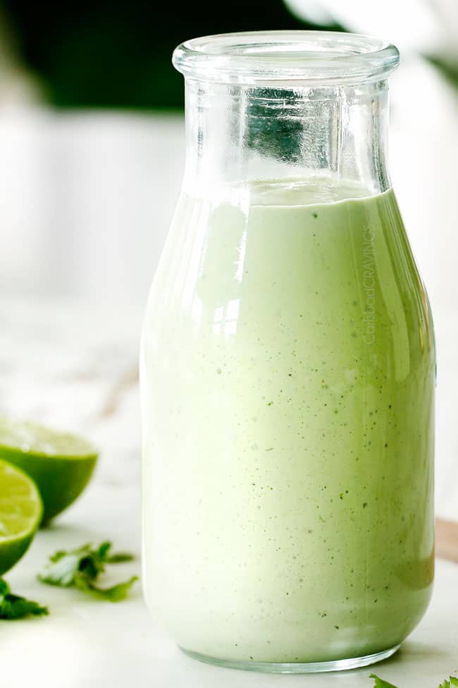Cilantro Lime Dressing in a glass jar on a white cutting board