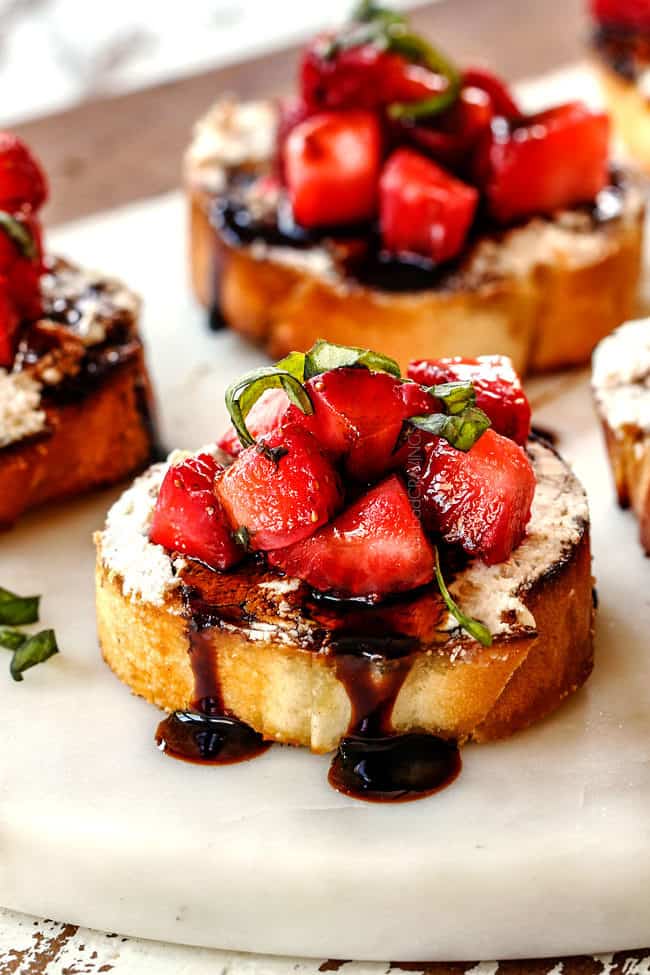 Strawberry Goat Cheese Bruschetta on a white cutting board with Balsamic Reduction