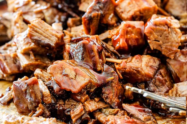 pulling apart barbecue brisket on a cutting board for Slow Cooker Beef Brisket Sandwiches