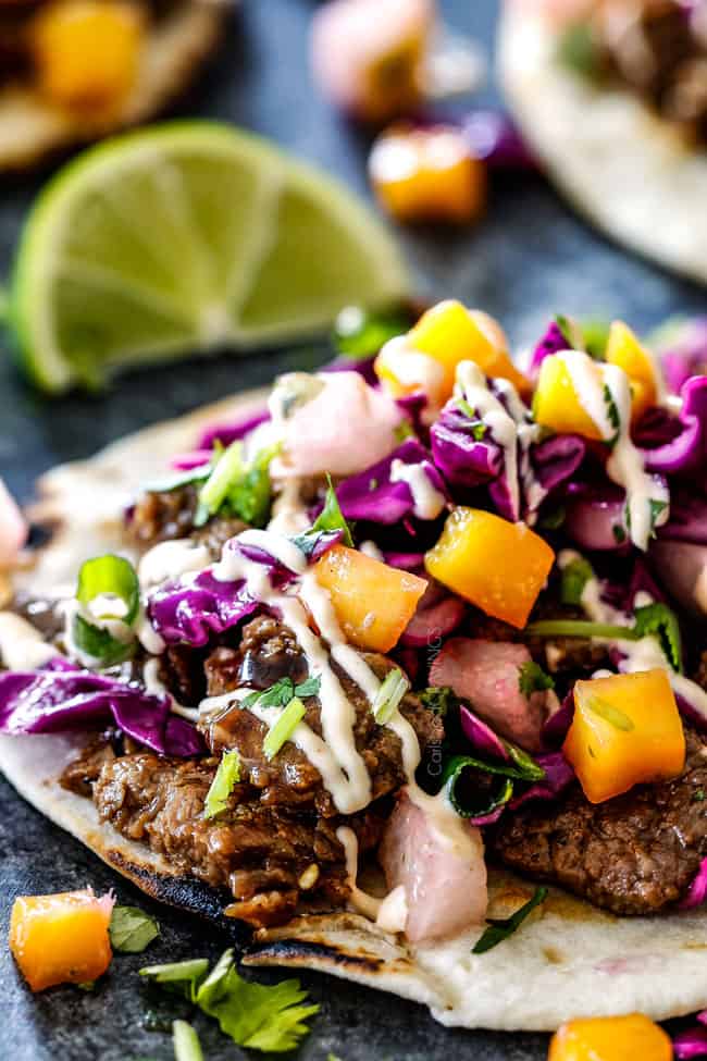 side view of steak Korean tacos laying flat with bulgogi beef, and Mango Pear Slaw