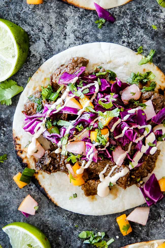 top view of Korean tacos with steak laying flat on a grey surface