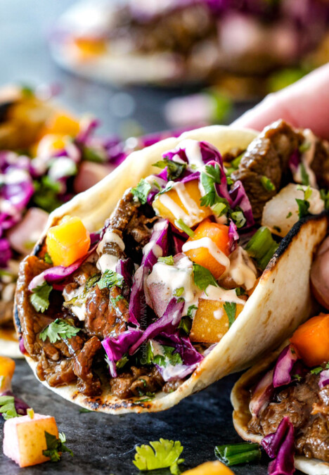 holding Korean Tacos with steak in one hand