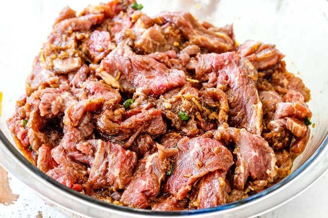 Showing how to make Beef Bulgogi by adding steak to marinade in a glass bowl
