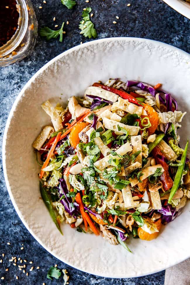 top view of crunchy Chinese chicken salad with mandarin oranges, peanuts napa cabbage, wontons, carrots, snow peas, red bell peppers all tossed together with sesame dressing