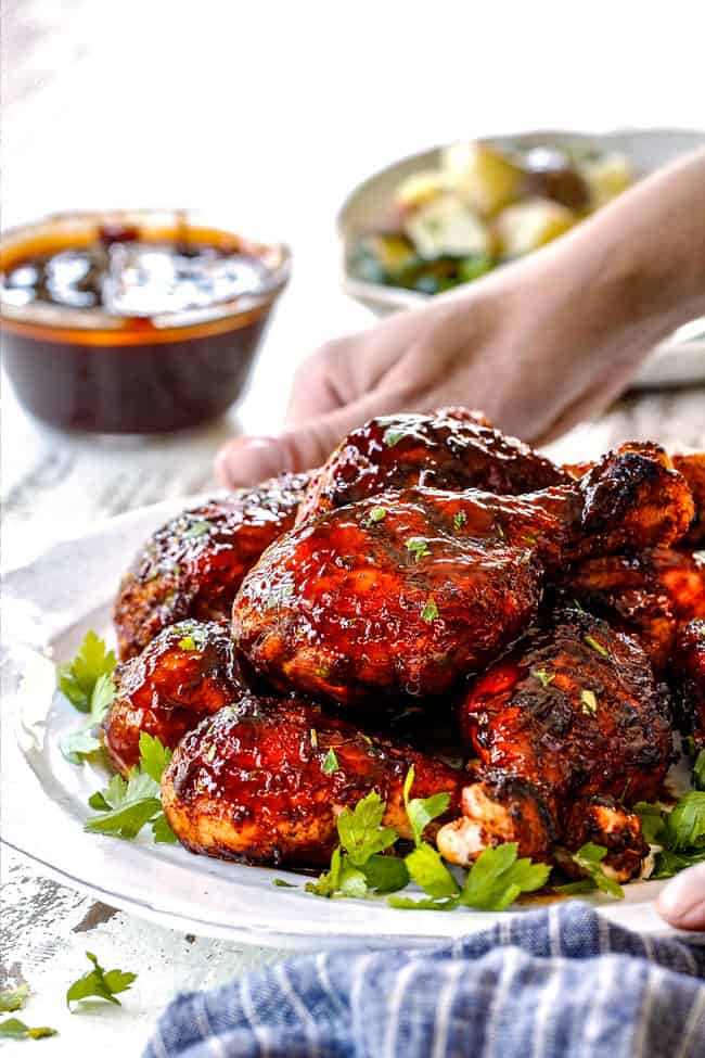 placing a platter of grilled bbq chicken on a table