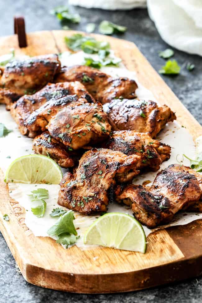 far away view of pile of lemongrass chicken with cilantro and lime on a cutting board