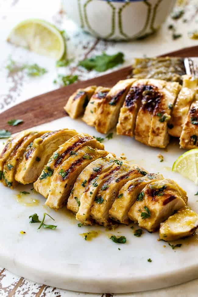 far away of two pieces of salsa verde chicken sliced on a cutting board