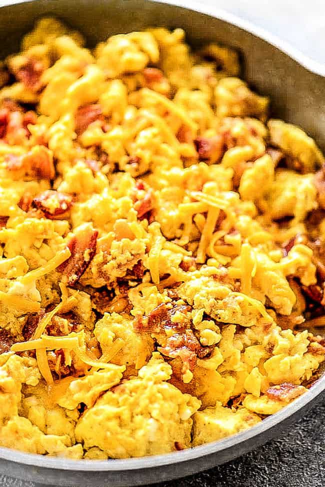 showing how to make breakfast burritos by scrambling eggs with bacon and cheese