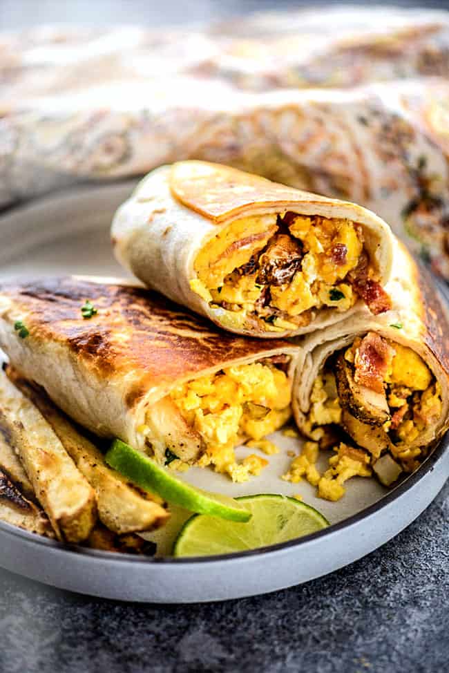 three halves of breakfast burritos on a plate with sauce