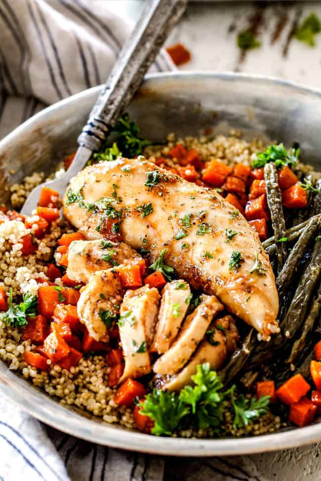 healthy sheet pan chicken and vegetables in a bowl with quinoa and a fork