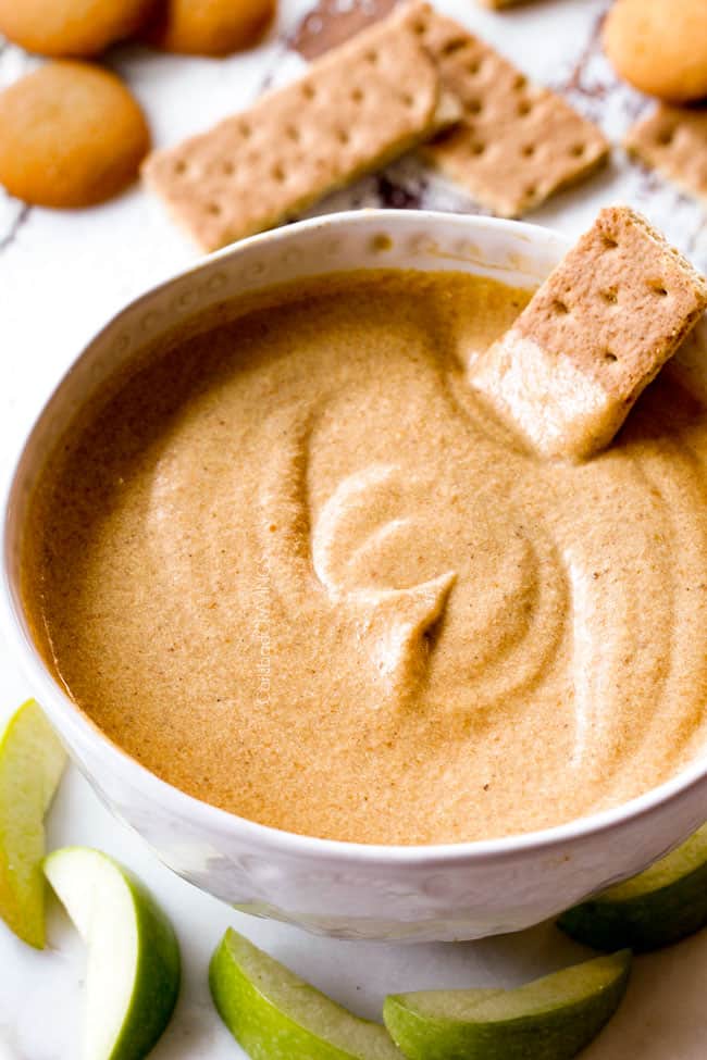 far away shot dipping a graham cracker into best pumpkin dip with cream cheese