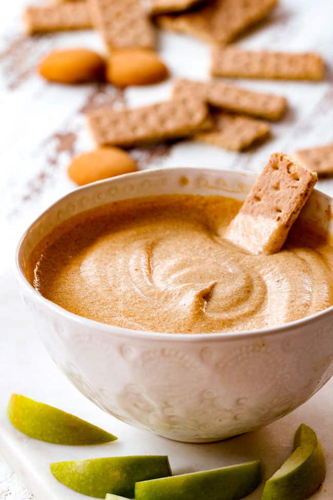 far away shot dipping a graham cracker into best pumpkin dip