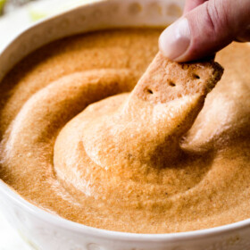 up close shot dipping a graham cracker into easy pumpkin dip
