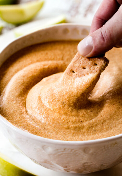 up close shot dipping a graham cracker into easy pumpkin dip